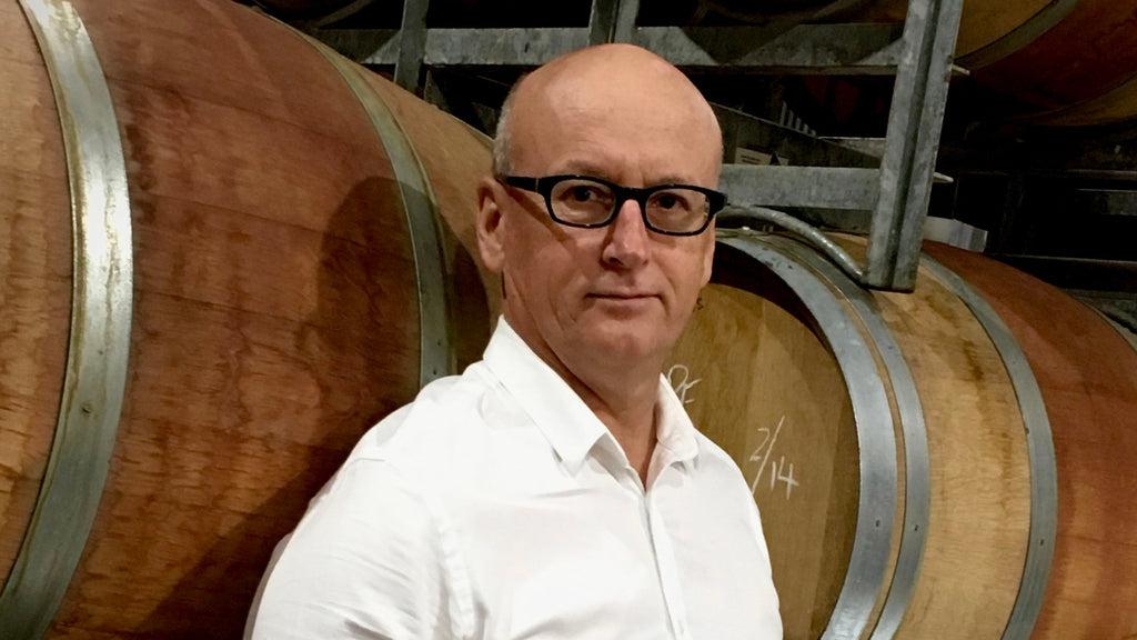 Wine barrels with a man in a white button-up shirt and black glasses