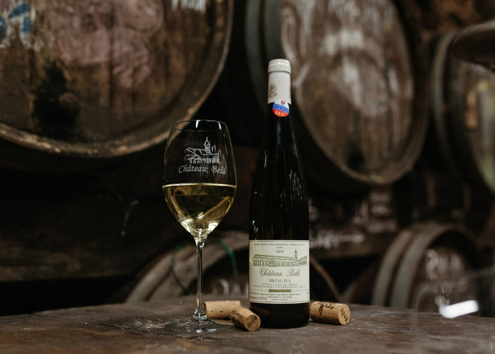 Riesling wine bottle with glass and two corks on table