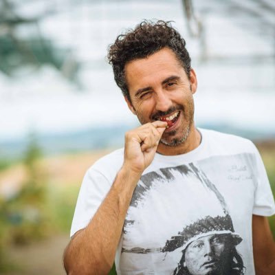 Man tasting wine, smiling with hand near mouth