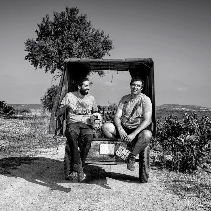 Two men in open wagon with dog in vineyard, Rioja Tempranillo wine scene
