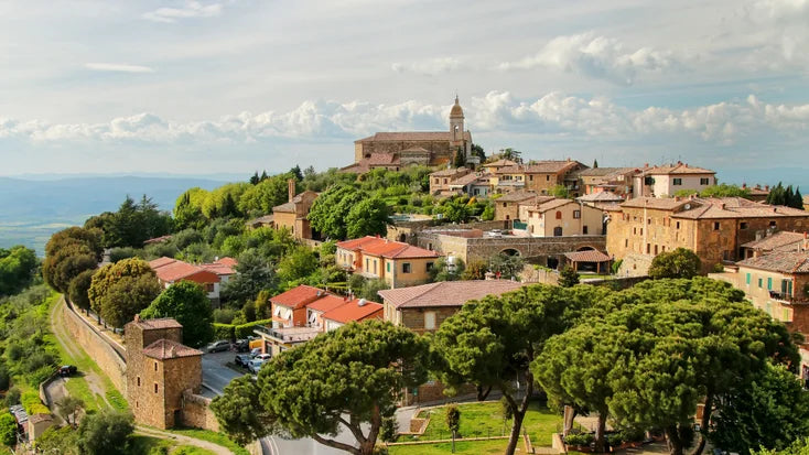 Tuscan hillside village with trees, terracotta roofs, and a church tower