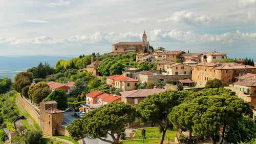 Tuscan hillside village with trees, terracotta roofs, and a church tower