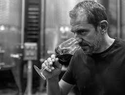 Man sipping wine from a glass in a cellar