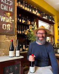 Man holding a Garnacha wine bottle with red cap and dark glass