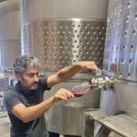 Winery worker adjusting stainless steel fermentation tank equipment