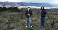 Two people standing outdoors in hilly vineyard landscape, Rioja Tempranillo wine scene